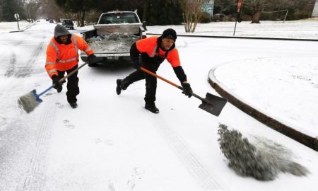 trabajadores echan sal y arena sobre la nieve